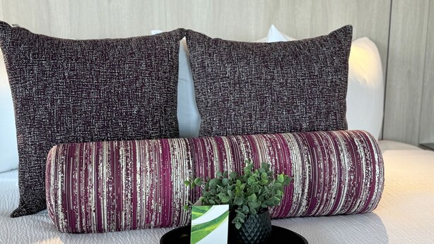 A bed with two square pillows and a cylindrical pillow. - Coast Edson Hotel (Edson)