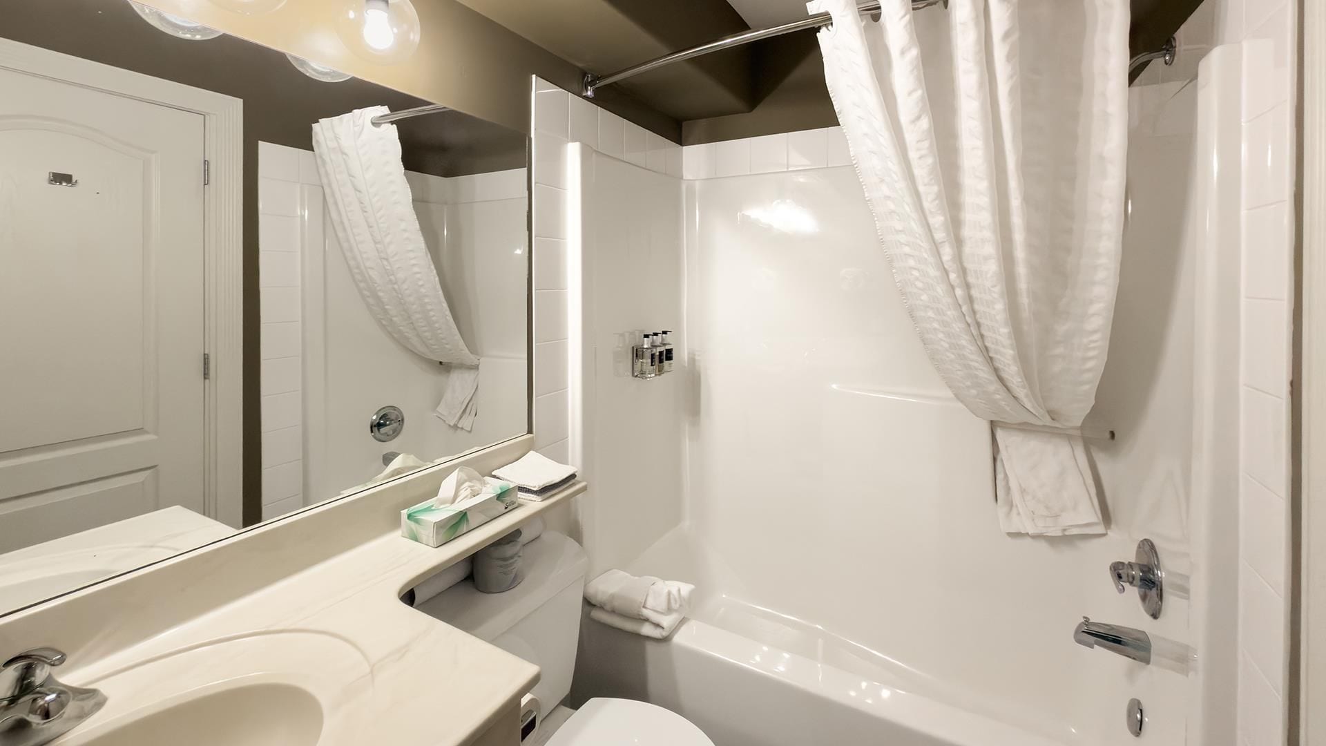 Un baño con bañera, inodoro, lavabo y espejo.