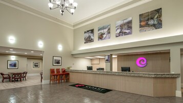 Un espace d’accueil d’hôtel comprenant un comptoir de réception, un coin salon et des œuvres d’art accrochées aux murs.