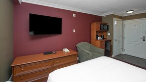 A hotel room with a bed, a dresser, a television mounted on the wall, a microwave, and a door. - Coast Edson Hotel (Edson)