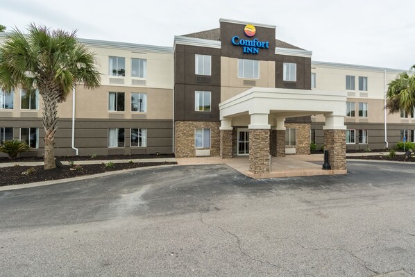 A Comfort Inn hotel with a modern design, featuring a two-story structure, a covered entrance, and a landscaped area with palm trees.