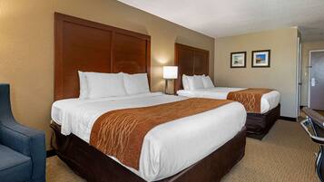 A hotel room with two beds, a desk, and a chair.