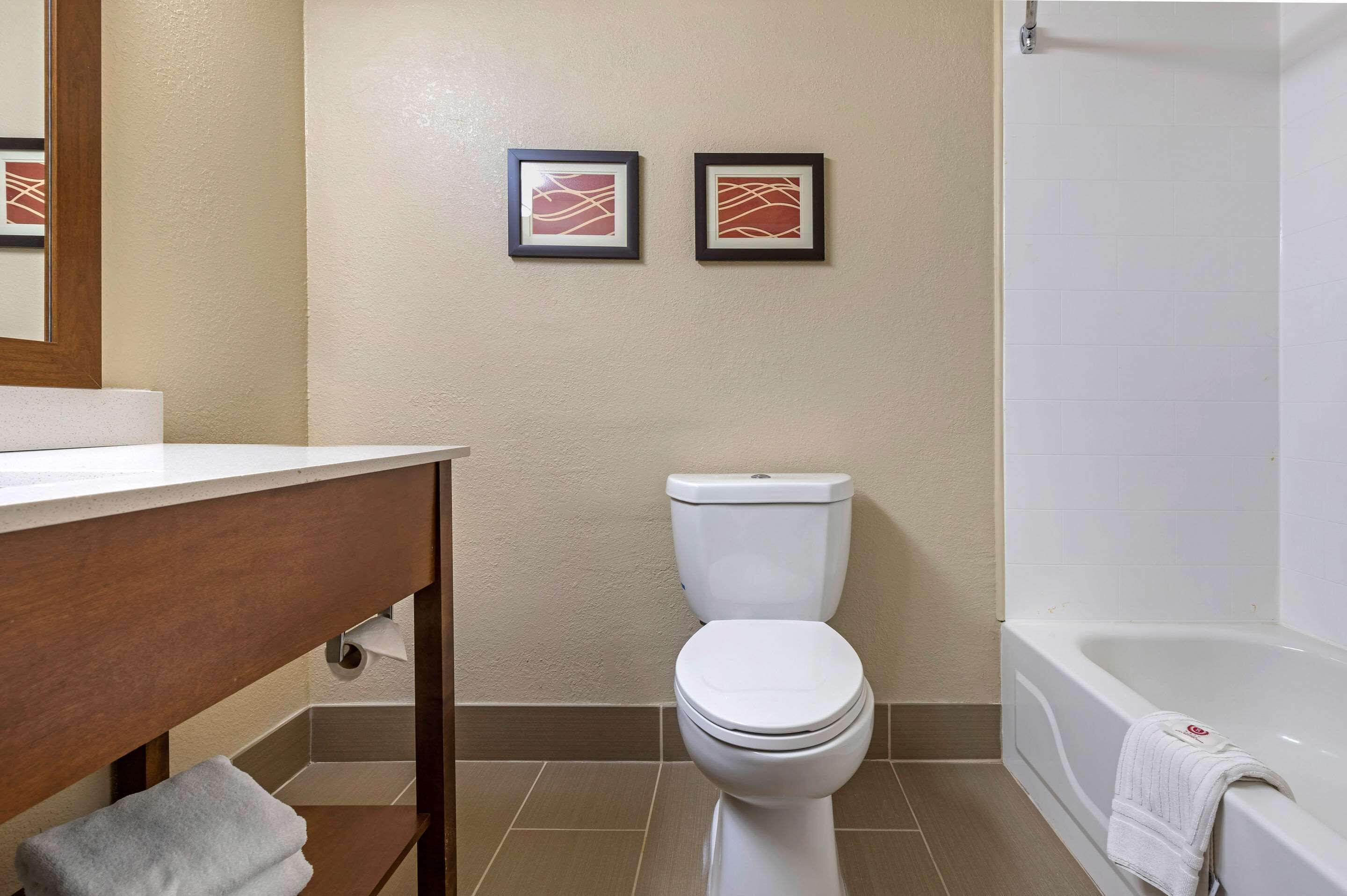 Une salle de bain équipée de toilettes, d’une baignoire et de deux tableaux encadrés accrochés au mur.