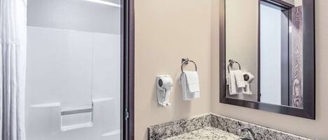 Un baño con ducha, un lavabo con encimera de mármol, un perchero y un espejo.