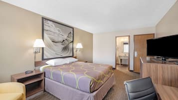 Una habitación de hotel con cama, dos lámparas de noche, un televisor, un escritorio y una silla.