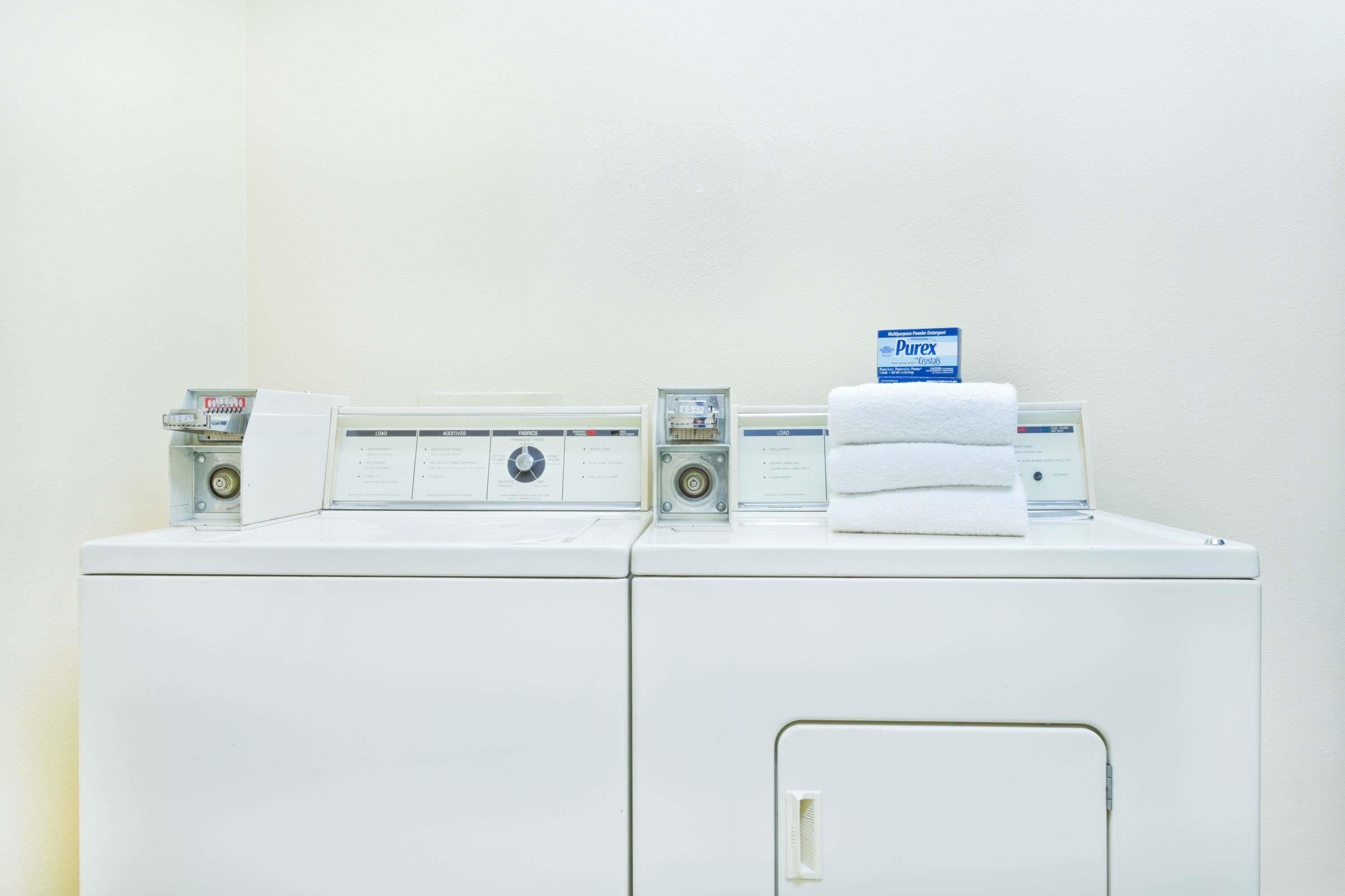 A front-loading washer and dryer unit with control panels and a stack of white towels on top.