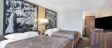 A hotel room with two beds, a television, a desk, and a large framed picture on the wall.