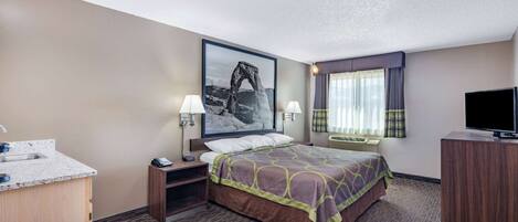A hotel room with a bed, a desk, a TV, a chair, a window with curtains, and a painting on the wall.