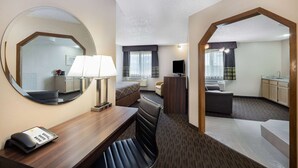 Una camera d'albergo con un letto, una scrivania con lampada, uno specchio, una TV, un divano e un angolo cottura.