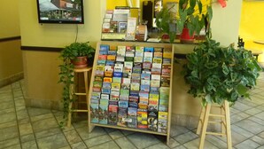 A reception desk with a map display, a television, and potted plants. - Motel 6 Wilsonville, OR - Portland (Wilsonville)