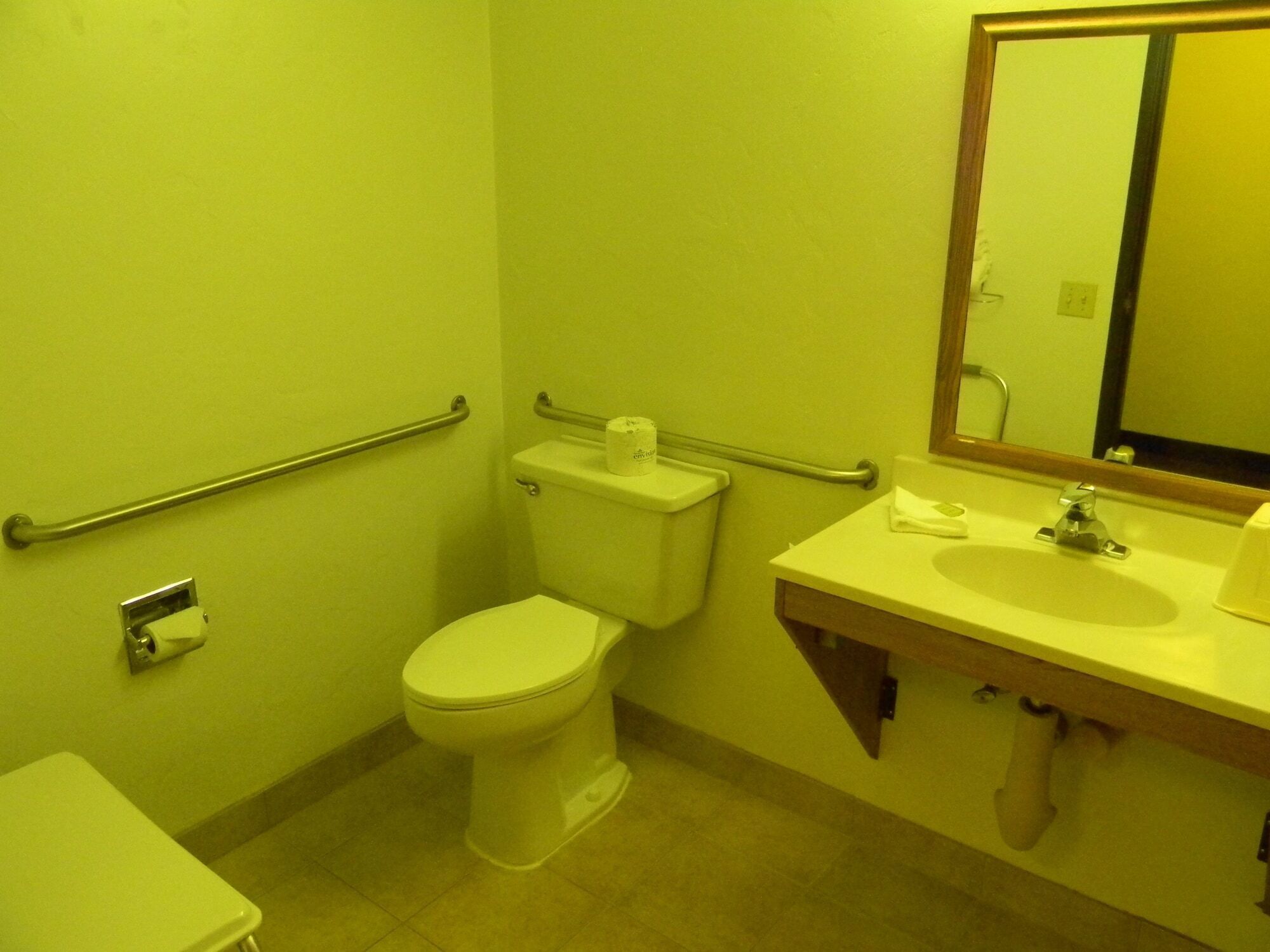 A small bathroom with a toilet, a sink, and a mirror.