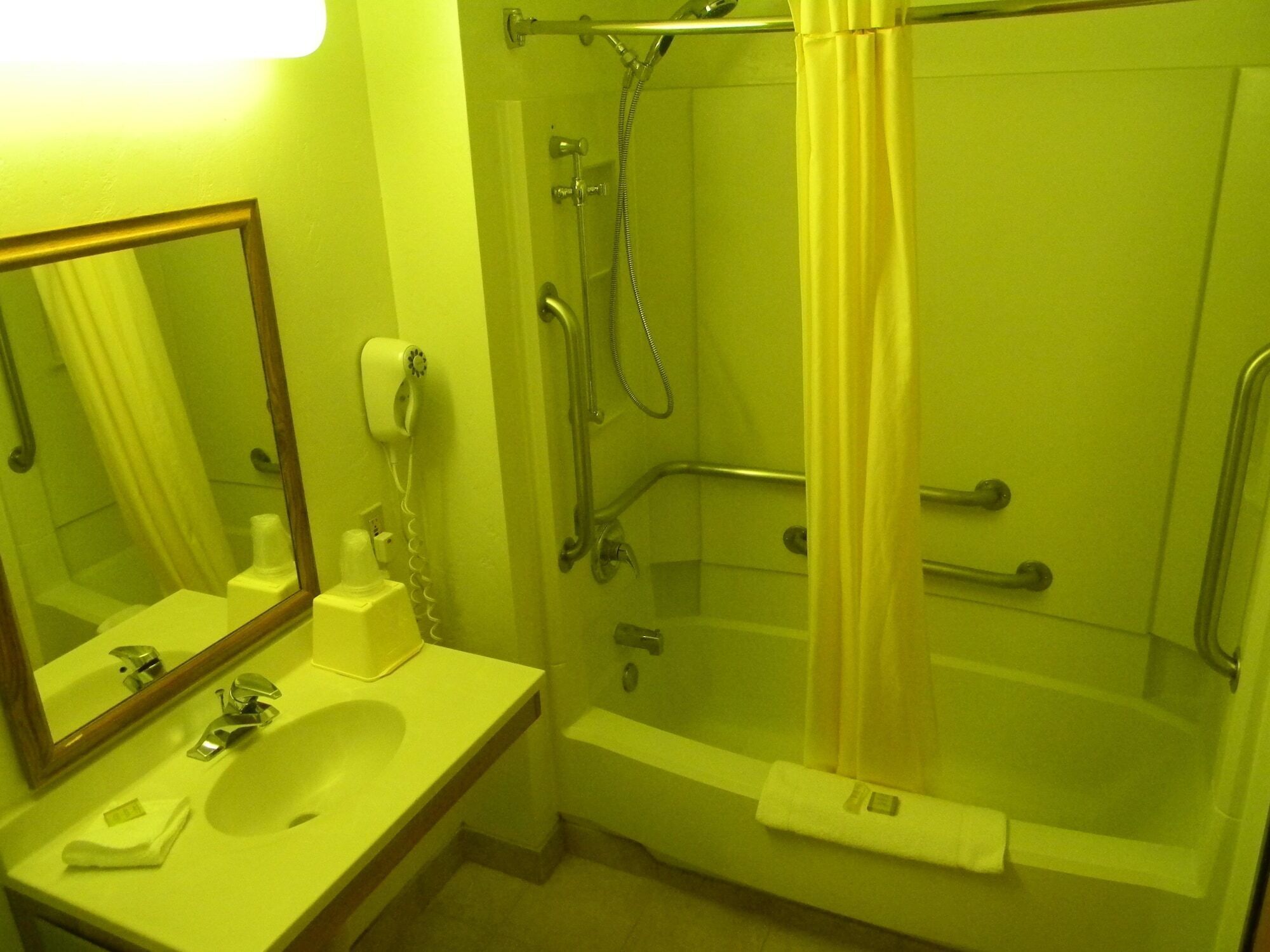 A bathroom with a sink, mirror, shower, and toilet.