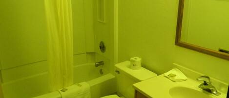 A small, compact bathroom with a toilet, sink, and shower.