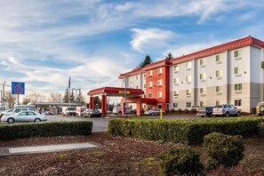 A hotel with a red and white exterior, a gas station in front, and several parked cars. - Motel 6 Wilsonville, OR - Portland (Wilsonville)