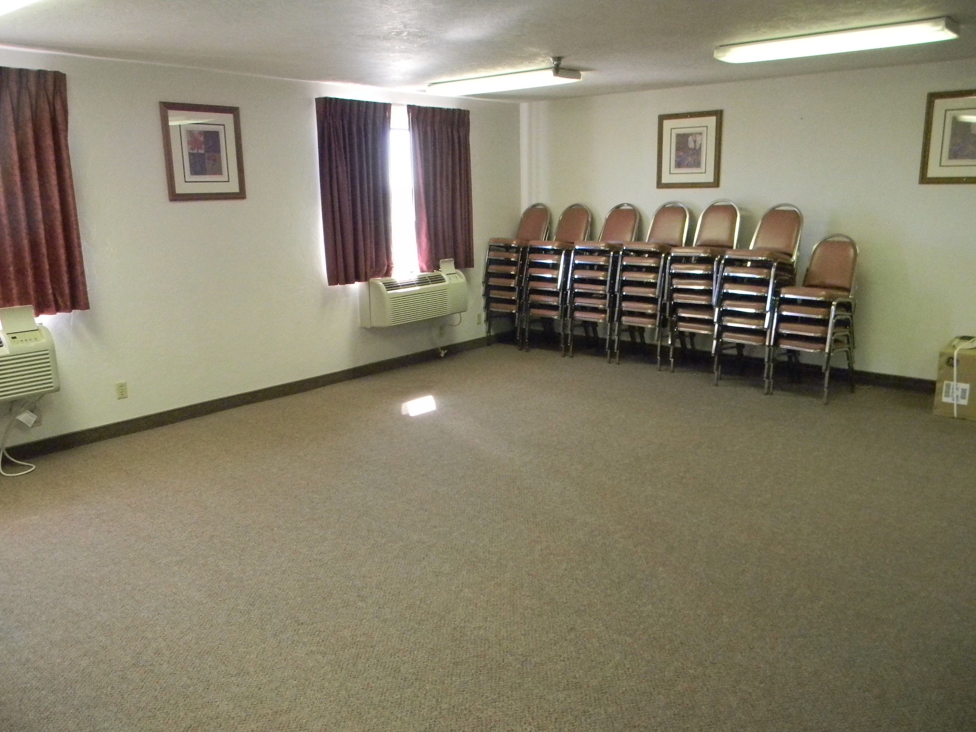 A conference room with a row of chairs, a ceiling fan, and two air conditioning units.