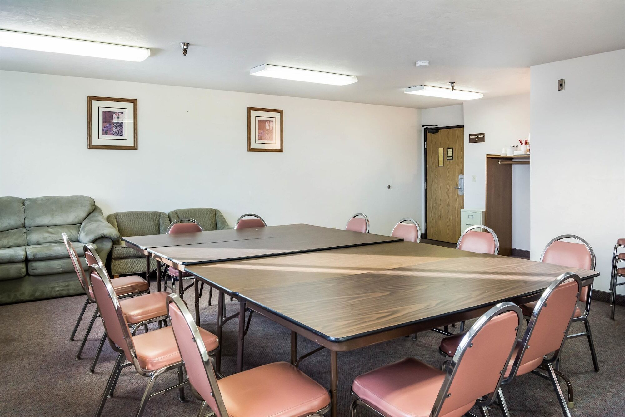 A conference room with a large table, several chairs, a sofa, and framed pictures on the walls.