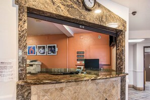 A hotel reception area with a marble counter, a clock, and a sign indicating the hotel name. - Motel 6 Wilsonville, OR - Portland (Wilsonville)