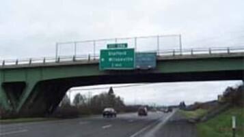A highway overpass with a green sign indicating directions to Springfield and Bloomington.