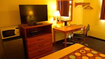 A hotel room with a bed, a desk, a chair, a television, a microwave, and a small refrigerator.