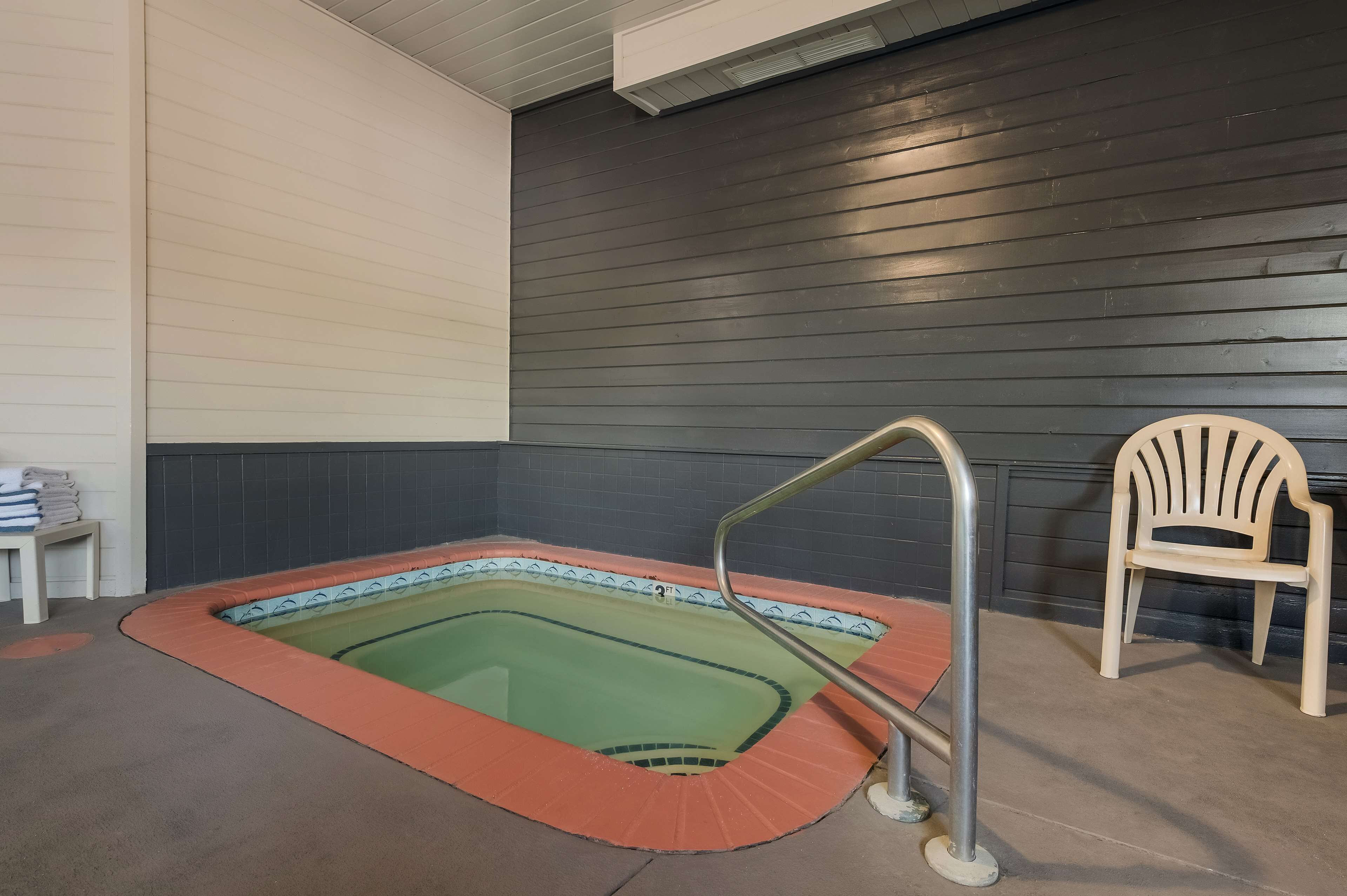 An indoor swimming pool with a metal ladder and a chair.