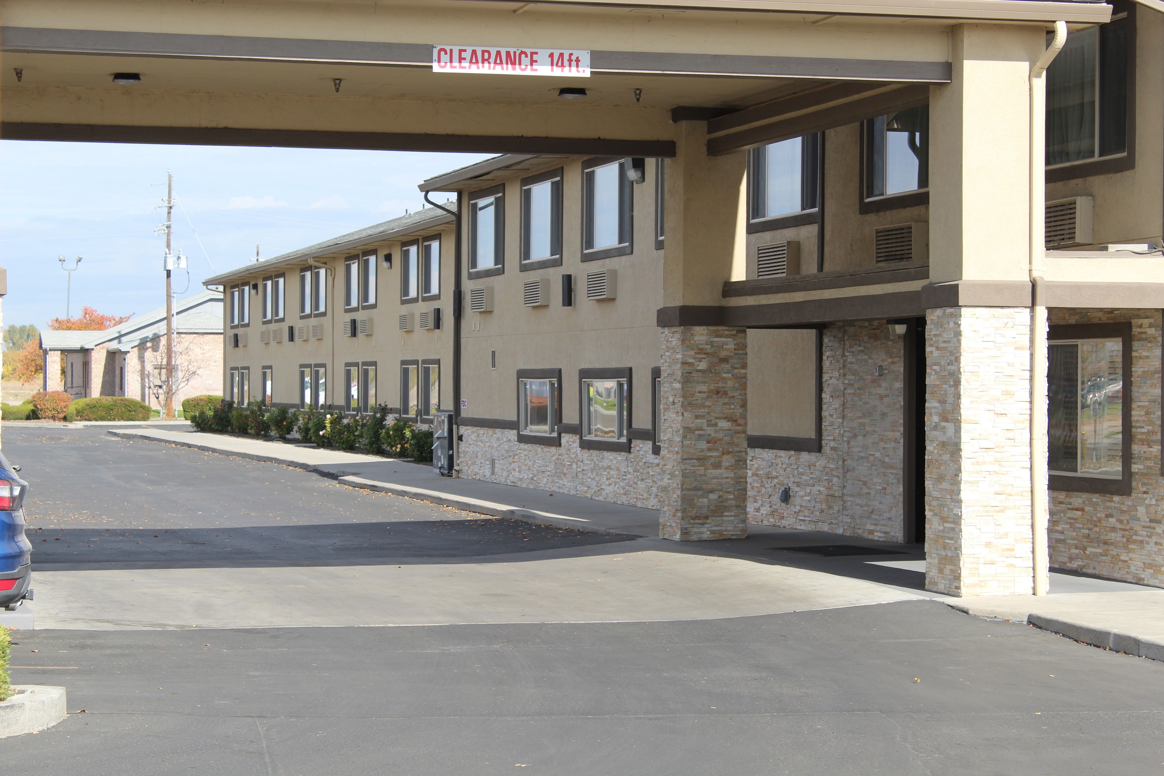 A building with a sign indicating a 14-foot clearance. It features a flat roof, multiple windows, and a brick facade.