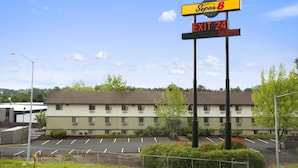 Un motel Super 8 con un estacionamiento y un edificio de múltiples ventanas y detalles verdes.