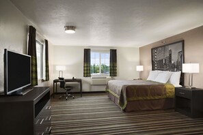 A hotel room with a bed, desk, chair, television, and a window with curtains.