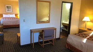 Een hotelkamer met een bed, een bureau, een stoel, een spiegel en een badkamer zichtbaar door een geopende deur.