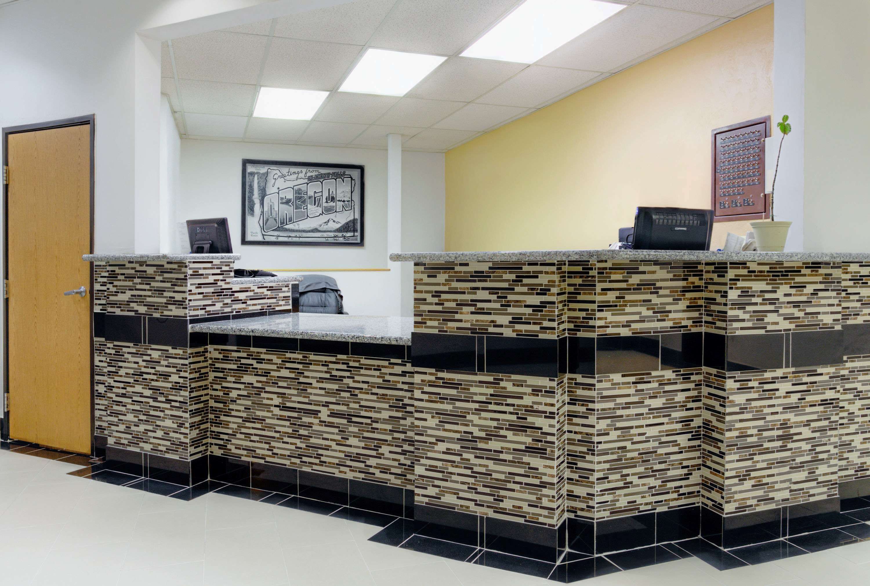 A reception area with a tiled counter, a framed picture on the wall, and a door to the left.