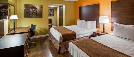 A hotel room with two beds, a desk, a chair, a lamp, and a painting on the wall.