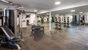 Un gimnasio con equipo de levantamiento de pesas, pelotas de ejercicio y un muro con espejos.