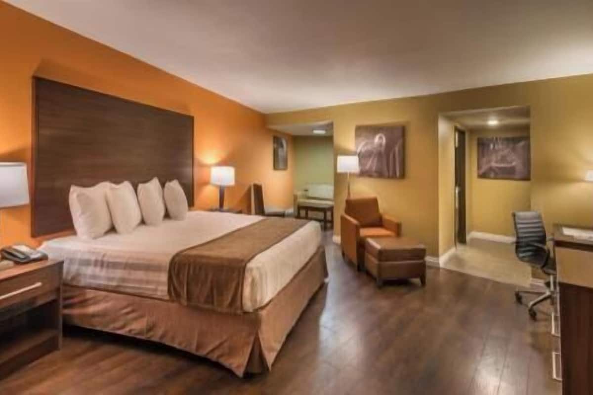Une chambre d’hôtel avec un lit, un bureau, une chaise et une petite table.