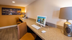 Habitación de hotel con escritorio, computadora, lámpara y una silla.