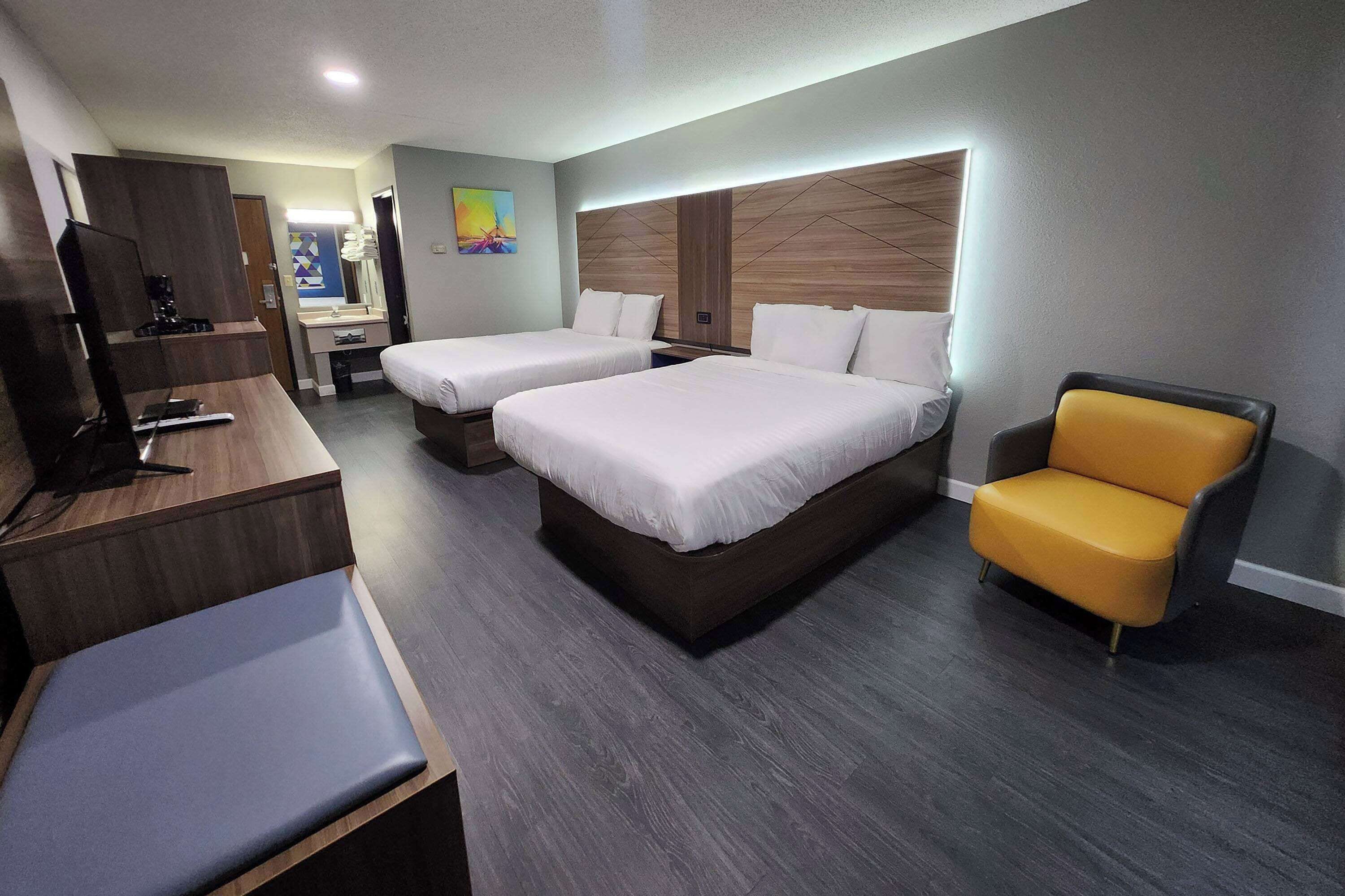 A hotel room with two beds, a desk with a computer, a chair, and a TV.