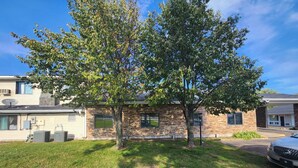 Un bâtiment en pierre de deux étages, avec un grand arbre devant.
