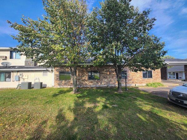Un bâtiment en pierre de deux étages, avec un grand arbre devant.