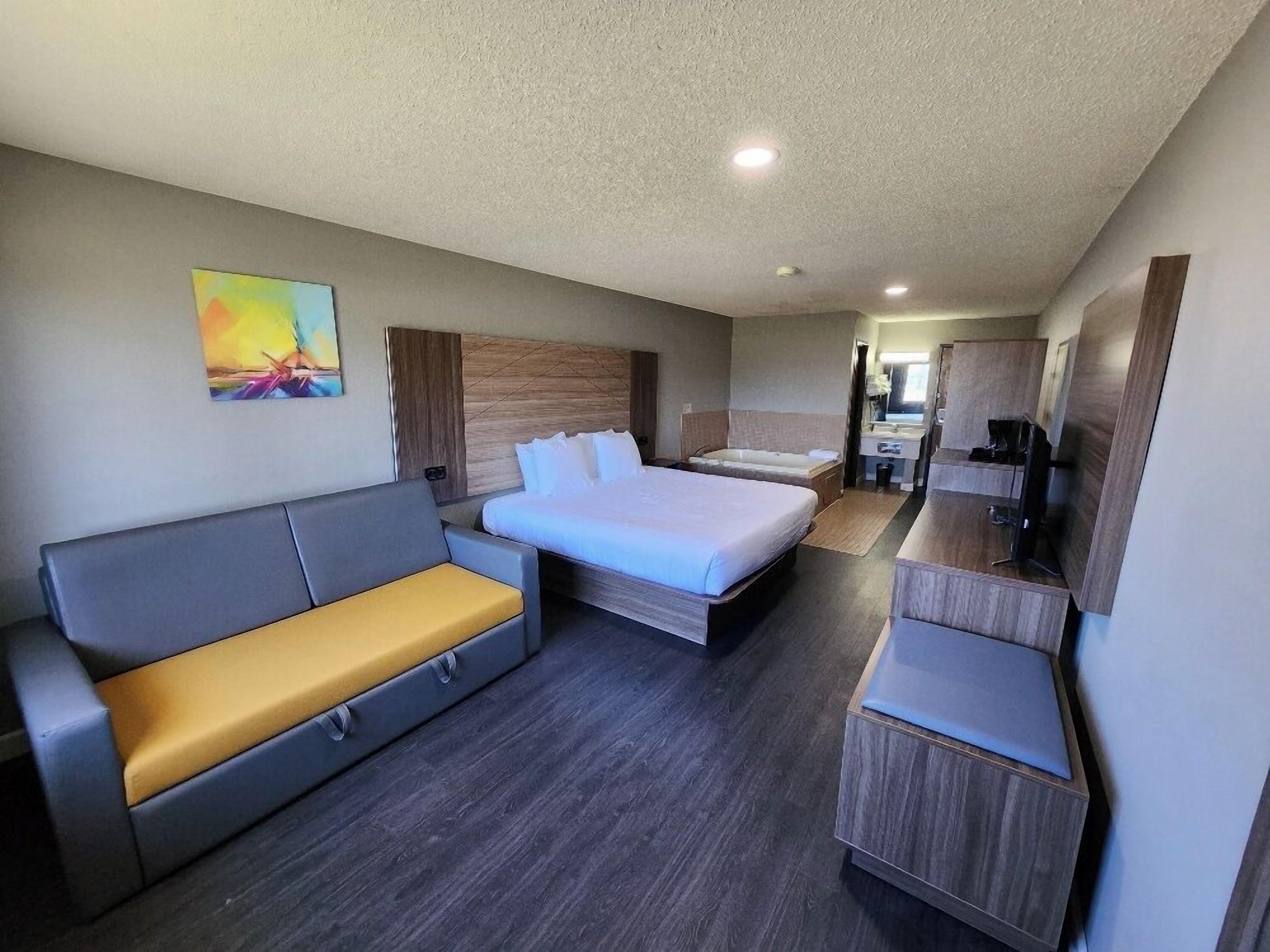 Quarto de hotel moderno com cama, sofá, escrivaninha e banheiro.