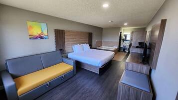 Quarto de hotel moderno com cama, sofá, escrivaninha e banheiro.