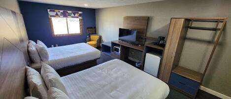 A hotel room with two beds, a TV, a desk, and a wardrobe.