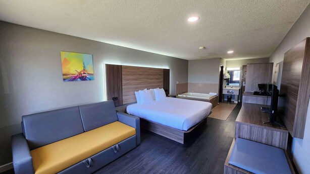 Une chambre d’hôtel moderne, dotée d’un grand lit, d’un canapé, d’un bureau et d’une télévision.