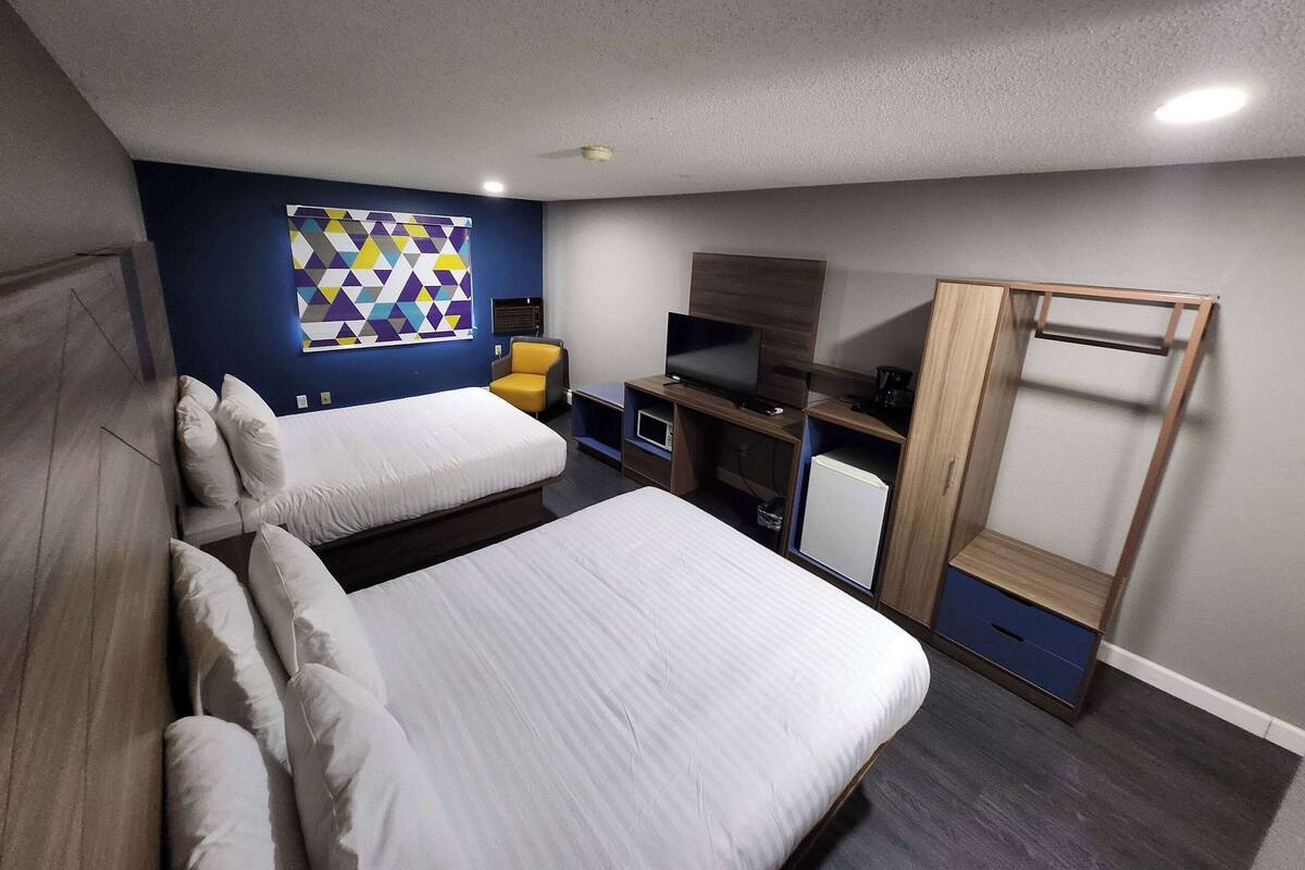 A hotel room with two beds, a TV, a desk, and a wardrobe.
