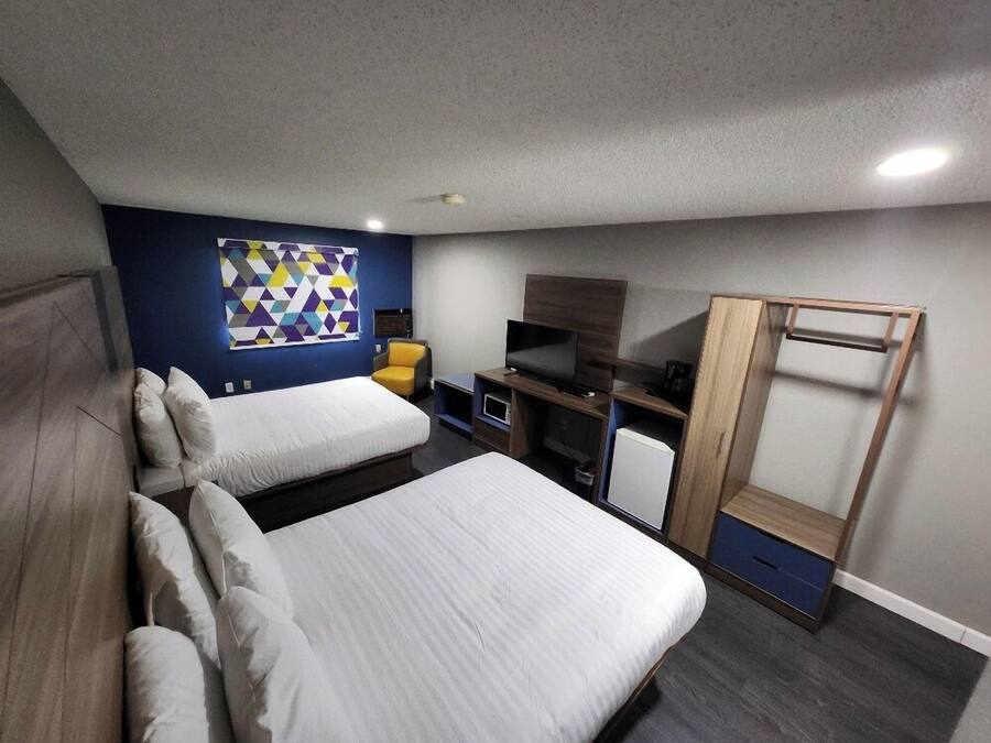 A modern hotel room with two beds, a TV, a desk, and a wardrobe.