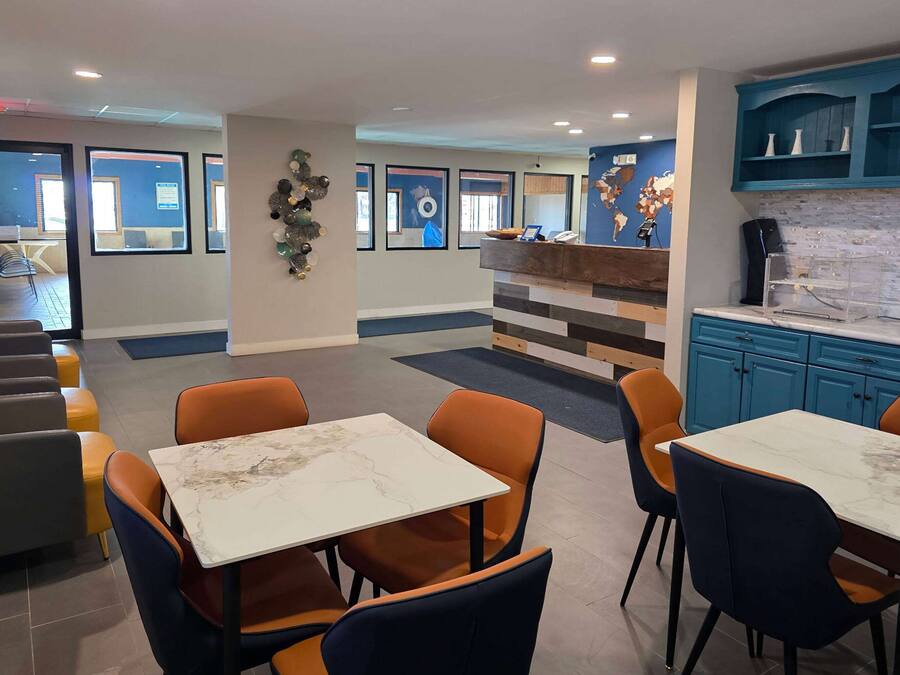 A modern hotel lobby with seating areas, a reception desk, and a kitchen area.