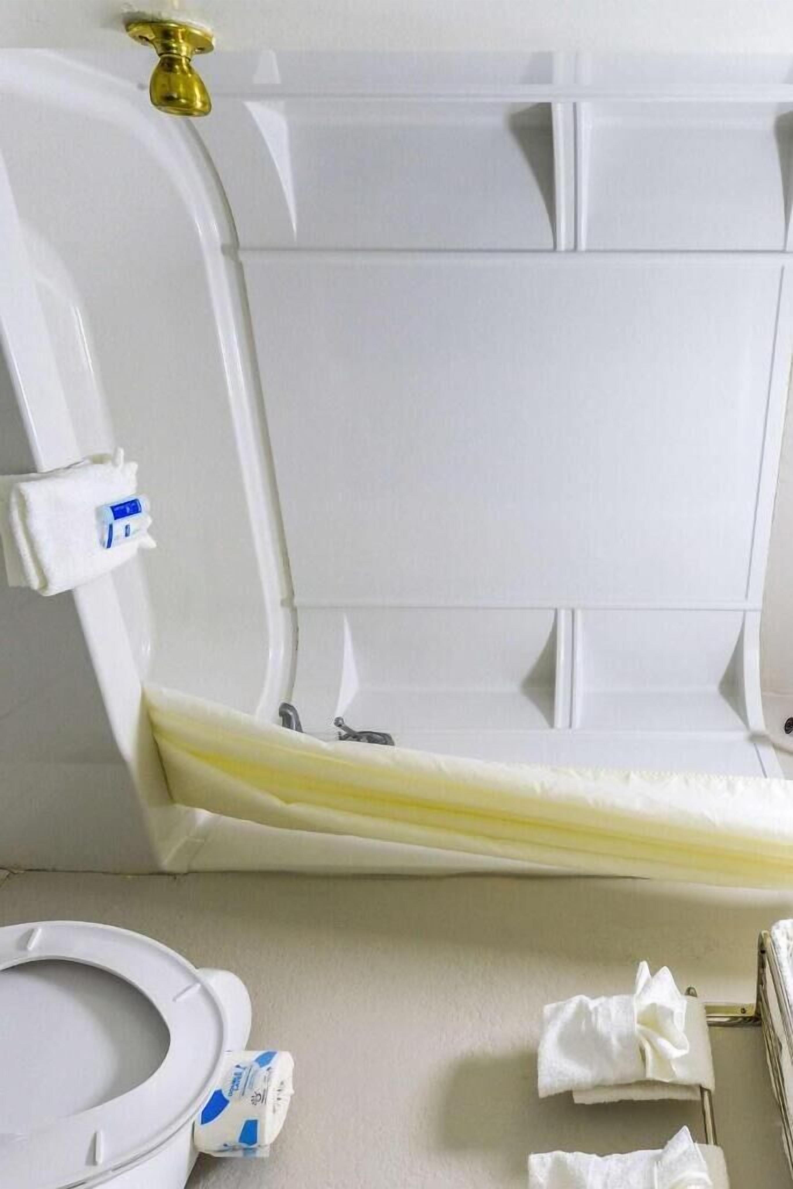 A bathroom with a white bathtub, a white toilet, and a towel rack with towels.