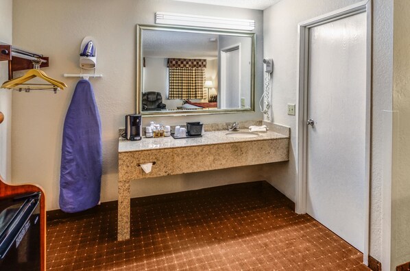 Une salle de bain d’hôtel équipée d’un lavabo, d’un miroir et d’un porte-serviettes.