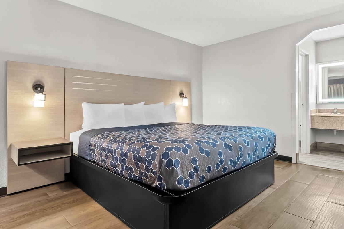 A modern hotel room with a large bed, bedside tables, and a built-in bench.