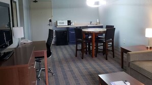 A hotel room with a dining area, a TV, a desk, and a sofa. - AmericInn by Wyndham Mauston (Mauston)
