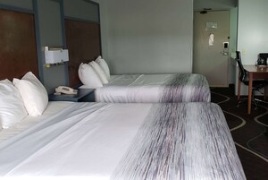 Habitación de hotel con dos camas, un escritorio, una silla y una cafetera.