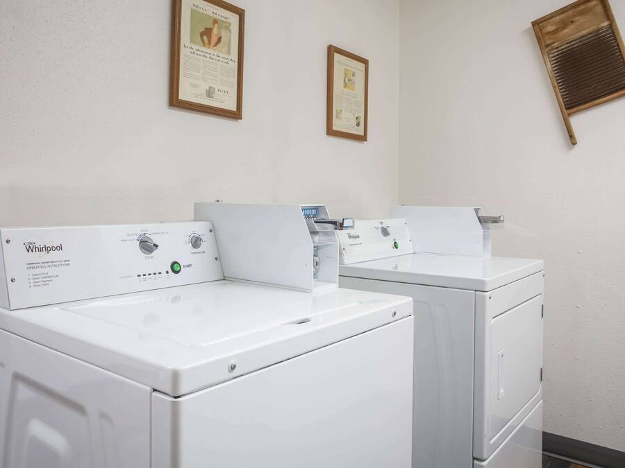 Two Whirlpool front-loading washing machines in a laundry room with framed certificates on the wall.