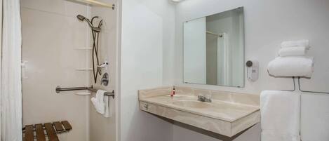 Un baño con ducha, lavabo, espejo y toallero.